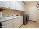 Functional laundry room with white cabinets, sink, and modern washer and dryer units at 17553 N Thornberry Dr, Surprise, AZ 85374