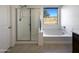 Bathroom featuring a soaking tub, a walk-in shower with glass door, and a window at 20033 N Herbert Ave, Maricopa, AZ 85138