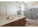 Bathroom featuring dual sinks, wood cabinets, and a shower-tub combo with patterned curtain at 23689 W Watkins St, Buckeye, AZ 85326