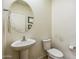 Clean half bathroom with a pedestal sink, round mirror, and a toilet at 23689 W Watkins St, Buckeye, AZ 85326