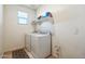 Functional laundry room with washer, dryer, storage shelf, and practical tile flooring at 23689 W Watkins St, Buckeye, AZ 85326