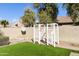 Spacious backyard featuring artificial grass, mature trees, and a decorative white trellis at 2428 E Iris Dr, Chandler, AZ 85286