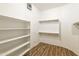 Bright walk-in closet with built-in shelving, hanging rods and wood style flooring at 2428 E Iris Dr, Chandler, AZ 85286