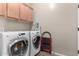 A laundry room with a washer and dryer set, upper cabinets, and gray walls at 2798 W William Ln, San Tan Valley, AZ 85144