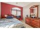 Cozy bedroom with red accent wall, wood furniture, and an arched window that offers natural light at 28549 N Dolomite Ln, San Tan Valley, AZ 85143