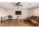 Spacious living room featuring hardwood floors, comfortable seating, ceiling fan, and a large television at 28549 N Dolomite Ln, San Tan Valley, AZ 85143