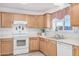 Functional kitchen featuring wooden cabinets, white appliances, and a bright window at 2900 E Paloma Rd, Eloy, AZ 85131