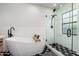 Modern bathroom featuring a freestanding tub, glass-enclosed shower, and stylish black-and-white tile flooring at 345 W Wilshire Dr, Phoenix, AZ 85003