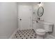 Well-lit powder room with a modern vanity, decorative mirror, and stylish black and white patterned tile floor at 345 W Wilshire Dr, Phoenix, AZ 85003