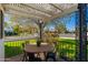 Cozy outdoor patio with a round table and chairs, shaded by a pergola and mature tree at 345 W Wilshire Dr, Phoenix, AZ 85003