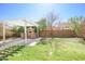 View of a backyard stone oven under a pergola with stone countertop and well-manicured lawn at 35771 W Costa Blanca Dr, Maricopa, AZ 85138