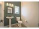 Stylish half bathroom featuring a pedestal sink, a modern toilet and a decorative mirror at 35771 W Costa Blanca Dr, Maricopa, AZ 85138