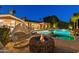 Backyard view of the pool, fire pit, spa, and a hanging chair, all surrounded by lush landscaping at 3937 E Norcroft Cir, Mesa, AZ 85215