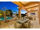 An outdoor patio featuring a dining area, a seating area with a TV, and a view of the pool at 3937 E Norcroft Cir, Mesa, AZ 85215