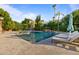 Inviting pool area featuring a rock waterfall, lush landscaping, and comfortable lounge chairs under sunny skies at 3937 E Norcroft Cir, Mesa, AZ 85215