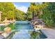 Luxurious pool with a rock waterfall feature and lush greenery, creating a serene and private backyard retreat at 3937 E Norcroft Cir, Mesa, AZ 85215