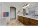 Well-lit bathroom featuring a double vanity with oak cabinets and an arched doorway at 40830 W Bedford Dr, Maricopa, AZ 85138