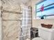 Modern bathroom with tiled shower, stylish shower curtain, and window providing natural light at 4929 W Christy Dr, Glendale, AZ 85304