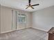 Bright bedroom featuring a ceiling fan, soft carpet, neutral walls, and a window dressed with curtains at 4929 W Christy Dr, Glendale, AZ 85304