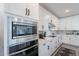 Modern kitchen featuring white cabinets, stainless steel appliances, herringbone backsplash and gray tile flooring at 5038 W Cheryl Dr, Glendale, AZ 85302