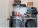 Laundry room with modern front loading washer and dryer set, and storage shelves at 5038 W Cheryl Dr, Glendale, AZ 85302