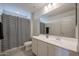 Bright bathroom with a large mirror, white cabinets, and a shower-tub combo with geometric curtains at 523 S 201St Ave, Buckeye, AZ 85326