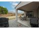 Relaxing covered patio area featuring a dining set and grill with landscaped backyard at 523 S 201St Ave, Buckeye, AZ 85326