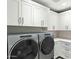 Modern laundry room featuring front load washer and dryer, shaker cabinets, and mosaic backsplash at 5541 E Stella Ln, Paradise Valley, AZ 85253