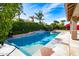 Relaxing backyard swimming pool with stone coping, lush landscaping, and clear blue sky at 6105 W Kimberly Way, Glendale, AZ 85308