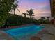 Backyard at dusk featuring sparkling pool, spa, and lush landscaping at 6105 W Kimberly Way, Glendale, AZ 85308