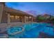 Backyard at dusk with swimming pool, spa, covered patio, and lush landscaping at 6105 W Kimberly Way, Glendale, AZ 85308