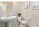 Cozy powder room features a pedestal sink, decorative mirror, and neutral color scheme at 6713 E Elmwood St, Mesa, AZ 85205