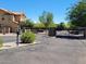 View of the community entrance with access gate surrounded by desert landscaping and lush mature trees at 6713 E Elmwood St, Mesa, AZ 85205