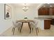 Cozy dining room with a round table, four chairs, chandelier, and adjacent kitchen with wooden cabinets at 7726 E Baseline Rd # 110, Mesa, AZ 85209
