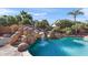 Close up of the pool with rock waterfall and slide feature, complemented by lush landscaping at 8421 W Alex Ave, Peoria, AZ 85382