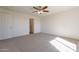 Large bedroom with plush carpeting, ceiling fan, and convenient access to an ensuite bathroom at 9705 E Butte St, Mesa, AZ 85207