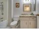 Bright bathroom with a bathtub, toilet, and modern vanity with a decorative mirror and granite countertop at 9806 W Long Hills Dr, Sun City, AZ 85351