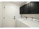 Laundry room featuring a white washer and dryer, black cabinets, and a door to the side of the house at 23843 N 73Rd St, Scottsdale, AZ 85255