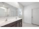 A bathroom with a double sink vanity, a large mirror, and neutral-colored tile floors at 24653 W Concorda Dr, Buckeye, AZ 85326