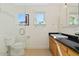 Bright bathroom featuring a black granite countertop, wood cabinets, and a pristine white sink and toilet at 318 E Concorda Dr, Tempe, AZ 85282