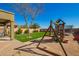 Backyard features artificial grass, a playset, mature landscaping, and a charming covered patio at 33731 N Slate Creek Dr, San Tan Valley, AZ 85143