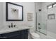 Bathroom with marble tile, glass shower doors, navy vanity, framed mirror and toilet at 3628 E Clarendon Ave, Phoenix, AZ 85018