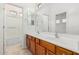 Bathroom with double vanity, large mirror, tile flooring, and shower behind glass doors at 3887 E Andre Ave, Gilbert, AZ 85298