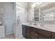 Well-lit bathroom featuring double sinks, a large mirror, and a tiled shower at 3973 N 310Th Ln, Buckeye, AZ 85396