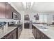 Modern kitchen featuring dark wood cabinetry, granite countertops, stainless steel appliances, and tile floors at 3973 N 310Th Ln, Buckeye, AZ 85396