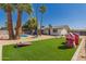 Lush backyard with an inground pool, shaded patio, cornhole game, and an artificial grass area at 4154 W Grovers Ave, Glendale, AZ 85308