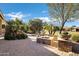 Green backyard featuring stone planters, fire pit, mature palms and an outdoor sitting area at 42920 W Kingfisher Dr, Maricopa, AZ 85138