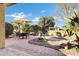 Lush backyard with a dining set, an umbrella, a rock garden and mature trees, perfect for outdoor entertaining at 42920 W Kingfisher Dr, Maricopa, AZ 85138