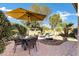 Well-maintained backyard with a dining set, an umbrella, a rock garden, and mature trees, creating a serene outdoor space at 42920 W Kingfisher Dr, Maricopa, AZ 85138