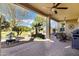 Relaxing covered patio featuring a ceiling fan, custom pavers, grill, rock garden, and ample seating space at 42920 W Kingfisher Dr, Maricopa, AZ 85138